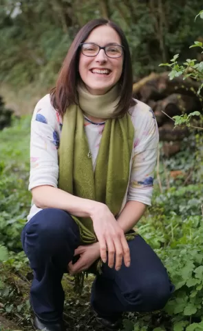 Cath, nature ni founder and forest school leader crouched in forest