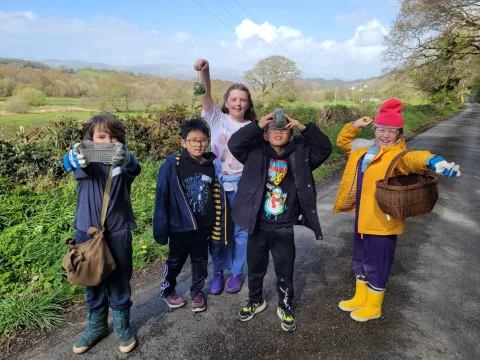 ChChildren smilling with their collected finds from foraging in woodland and meadow